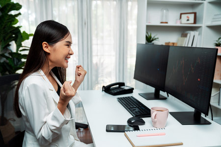 Successful young Asian businesswoman earning highest profit with fist up in exchange stock market on...