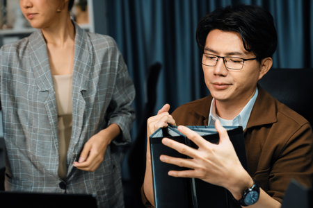 Managers discussing document paperwork together for business planning on market share data at late night time at modern home office, working on startup company deadline project job.の写真素材