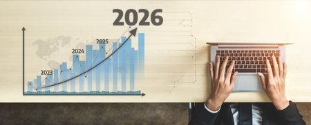 A professional business setting showcasing a laptop and a bar graph signifying growth projections for 2026, illustrating future trends and strategic planning.の写真素材