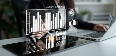 A business professional uses a laptop to engage in marketing planning, analyzing digital analytics...