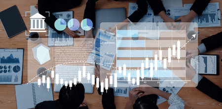 A top-down view of a business team engaged in analyzing various financial charts and reports,...