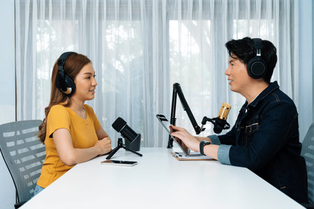 Smiling radio influencer host holding tablet wearing headphones interview woman speaker social media...