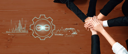 Diverse team members join hands on a wooden table, highlighting collaboration and innovation in...