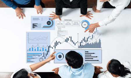A diverse business team collaboratively analyzing data charts and graphs on a table, engaging in...