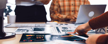 A dynamic group of business professionals engages in collaboration and discussion over charts and...