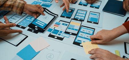 A dynamic workspace showcases hands engaged in a collaborative design process, creating mobile app...