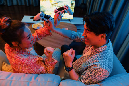 Couple gamer with hands cross of joystick playing fighting video game with winner together on tv...