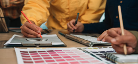 A diverse team of professionals actively collaborates on a design project, using color swatches and...