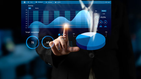 A businessperson uses a transparent touchscreen to interact with interactive graphs and charts,...