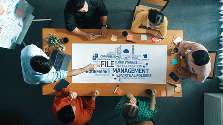 A diverse team collaborates around a table discussing file management, cloud storage, and...
