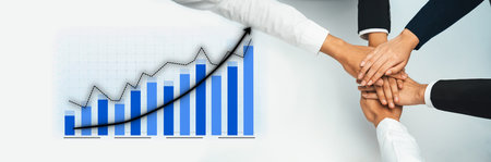 A close-up view of hands joining together in collaboration over a rising graph, symbolizing teamwork...
