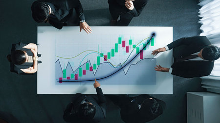 A diverse business team engages in a critical financial analysis meeting, focusing on graphs and...