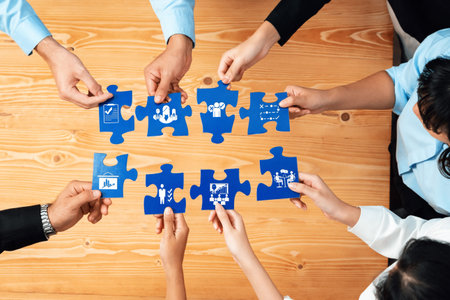 Diverse team members work together, holding puzzle pieces that symbolize business strategies,...