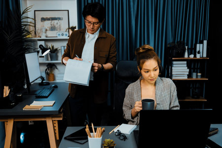 Businesswoman looking on laptop for thinking marketing online project while drinking coffee with...