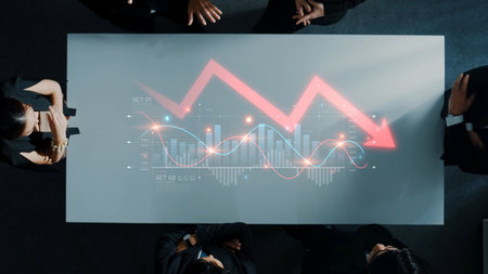 A dynamic business scene with a team analyzing financial data on a modern meeting table. Visuals include graphs and charts displaying a declining trend. Rasterの写真素材