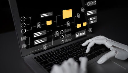 A robotic hand interacts with a laptop showcasing a data management interface filled with visuals and workflow elements, signifying automation in technology.の写真素材