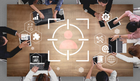 A top-down view of a diverse team working together at a modern office table, utilizing technology and data icons to enhance their marketing strategies and improve workflows.の写真素材