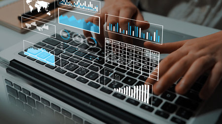 Hands typing on a laptop keyboard with data analysis graphics, business charts, and global maps for...