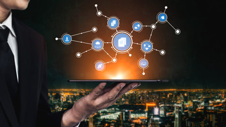 A businessman holds a tablet displaying glowing digital icons, representing connectivity and...