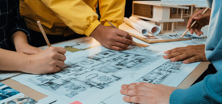 A dynamic scene showcasing hands actively engaged in sketching architectural plans during a...