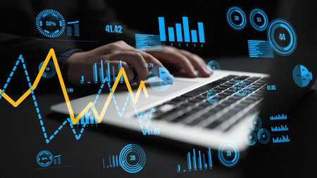 A business professional engages with data analysis using a laptop, surrounded by digital graphs and...