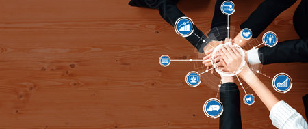 This image showcases hands coming together in unity on a wooden surface, surrounded by business...