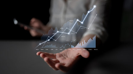 A business professional analyzes financial growth using advanced holographic graphs, showcasing dynamic trends while conveniently operating a smartphone for real-time insights.の写真素材