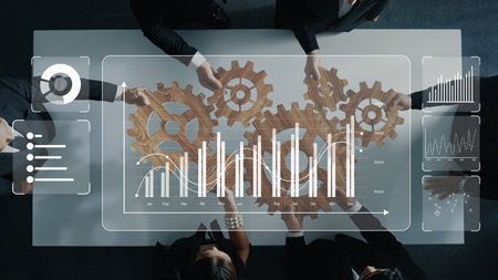 A diverse group of professionals collaborates over a table, working with gears and digital analytics...