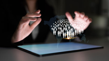 Hands of a business professional manipulating holographic human figures above a digital tablet displaying a global map concept of connectivity and networking.の写真素材