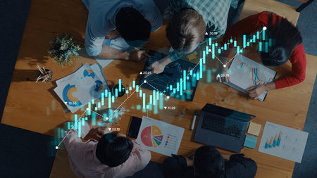 A diverse group of professionals collaborates over financial data analysis, surrounded by charts and...