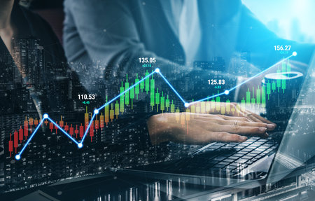Business professional analyzing stock market data on laptop with graphic financial charts,...