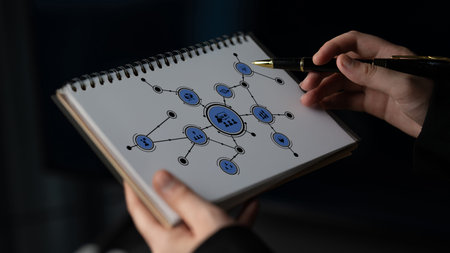 A person holds a notebook featuring a creative network diagram, illustrating connections and interactions. The setting highlights a dynamic and innovative workspace atmosphere. Tesselの写真素材