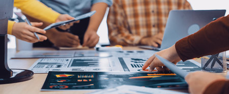 A diverse group of professionals collaborates during a business meeting, analyzing reports and...