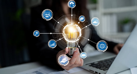 A businesswoman in a modern office environment holds a light bulb, surrounded by digital icons...