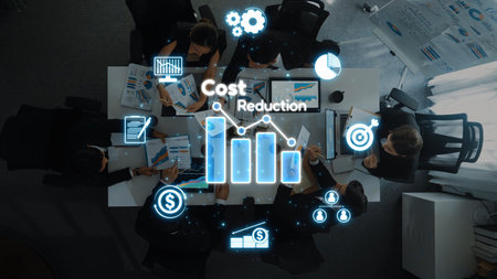 A professional business meeting centered on cost reduction strategies. Overhead view of a team...