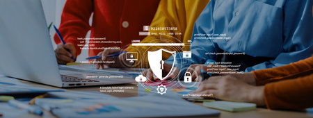 People collaborating in an office environment work on a laptop, showcasing cybersecurity themes and...