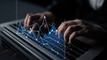 A businessman engages with financial data on his laptop, showcasing hands typing on the keyboard...