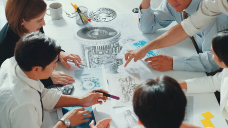 Top view of engineer pointing at turbine engine at meeting table with equipment. Aerial view of...
