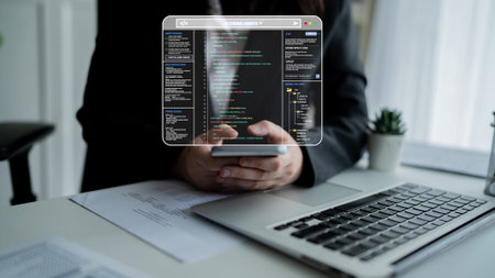 Digital Workspace with Coding Interface, Hands Holding Smartphone, Laptop and Indoor Plant in Modern...