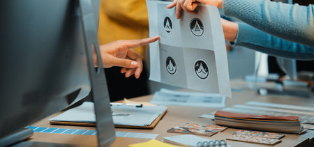 A vibrant office scene showcasing hands interacting with printed logo concepts during a design collaboration. The environment emphasizes teamwork and creativity.の写真素材
