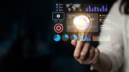 A close-up of a person holding a glowing light bulb with various data visualization elements. This...