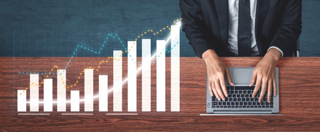 A businessman is focused on analyzing data trends on a laptop in a contemporary office setting, with...