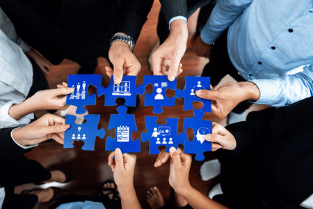 A diverse group of professionals collaboratively engaging with puzzle pieces that symbolize business strategies and teamwork in a modern office setting.の写真素材