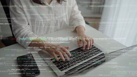 Close-up view of hands typing on a laptop keyboard amidst a backdrop of code, symbolizing remote...