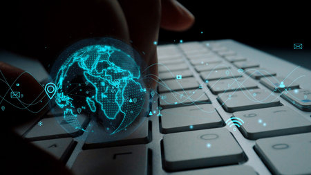 A close-up of a person hand interacting with a keyboard, surrounded by a digital globe and abstract...