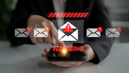 A professional individual interacts with a smartphone displaying an urgent warning alert for...