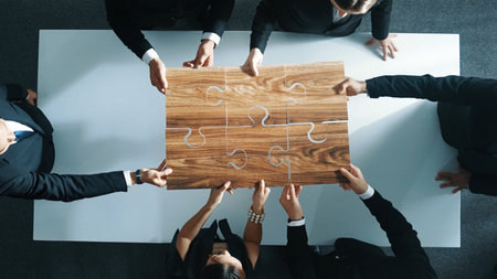 Skilled business people putting puzzle together at meeting table. Group of smart diverse business...