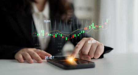 A focused business professional examines stock market data on a smartphone, showcasing digital...