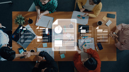 A diverse group of professionals collaborates at a modern office table, showcasing digital graphics...