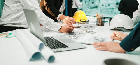 Team of professionals collaborating in a modern office, focusing on project planning with blueprints...